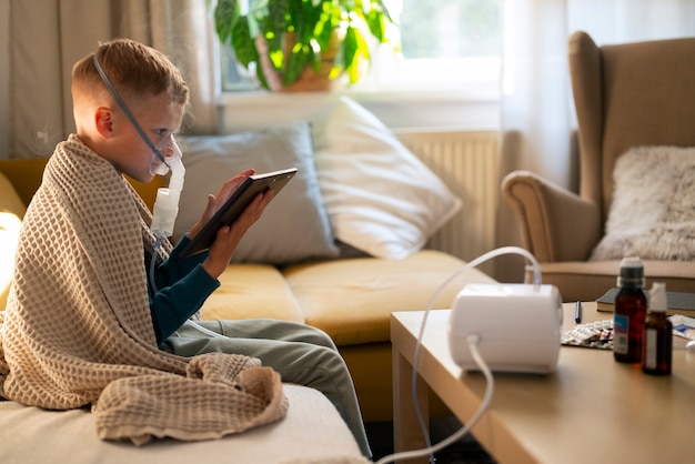 Free photo side view boy using a nebulizer