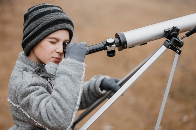 Side view boy using a telescope