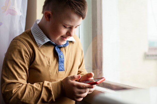 Side view of boy with down syndrome holding smartphone