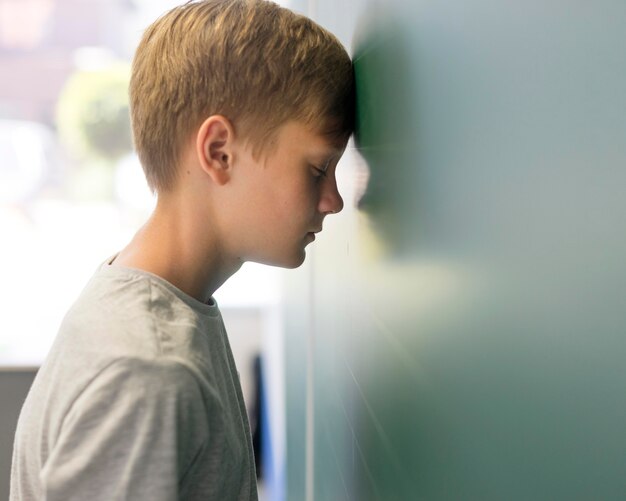 Side view boy with head lean on wall