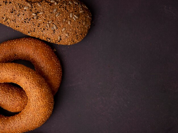 Side view of breads as bagel and sandwich bread on left side and maroon background with copy space