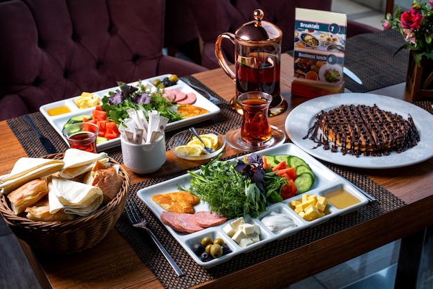 Side view of breakfast table served with various food dessert and tea