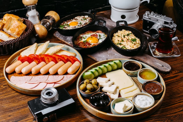 Side view of breakfast table with sausages fresh vegetables cheese ham and sauces jpg