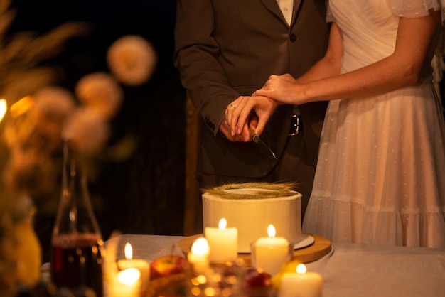 Side view bride and groom cutting cake