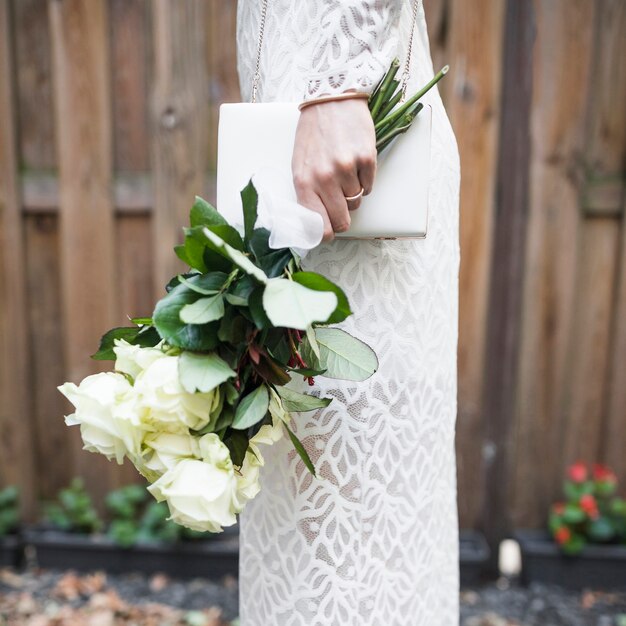 Side view of bride holding white roses and clutch