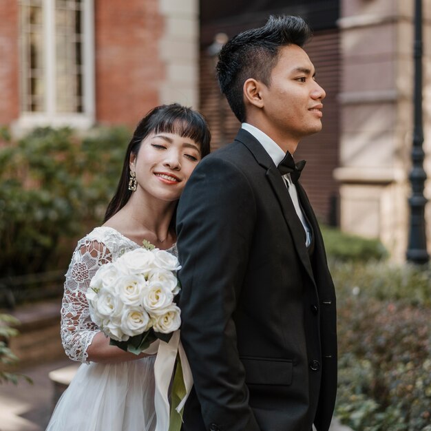 Side view of bride standing behind groom while holding bouquet