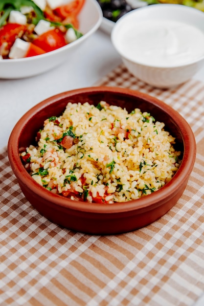 Side view of bulgur with tomatoes in a wooden bowl