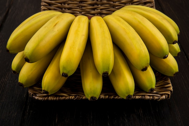 Side view of bunch of bananas in a wicker basket on dark