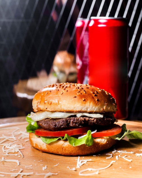 Side view of burger with beef meat melted cheese and vegetables on wooden board