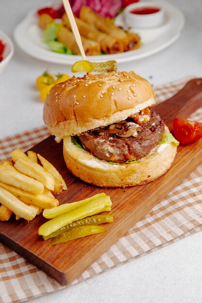 Side view of burger with french fries on a wooden board