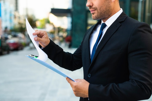 Side view business man reading from a clipboard