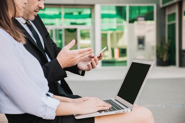 Free photo side view of business people sitting on bench with laptop