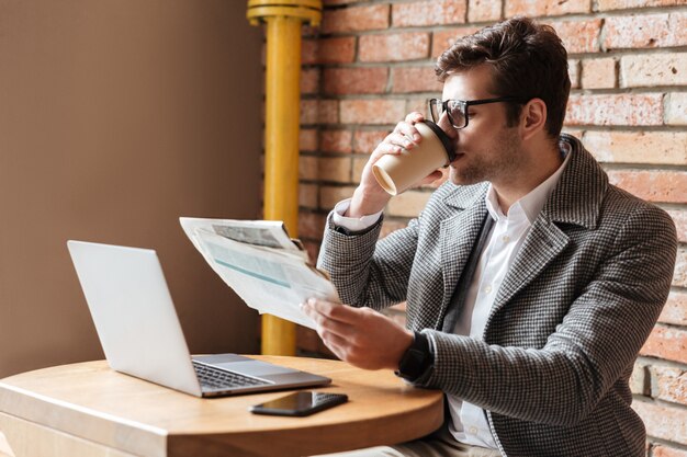 Side view of businessman in eyeglasses sitting by table