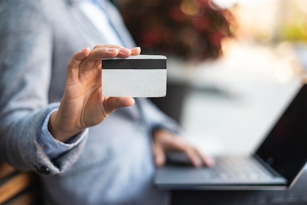 Side view of businesswoman holding credit card while using laptop