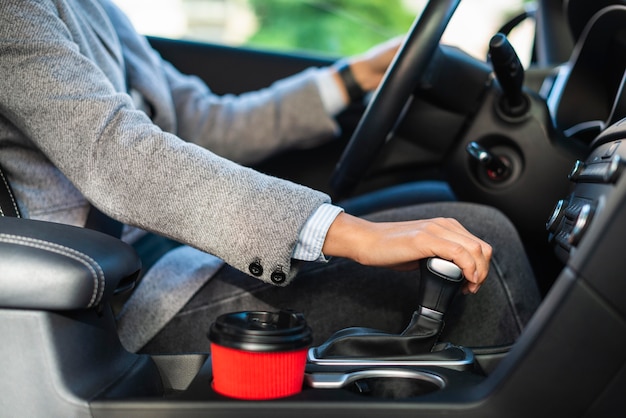 Side view of businesswoman using the stick shift of her car