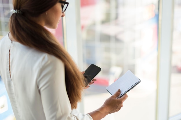 Side view of businesswoman with smartphone and notebook