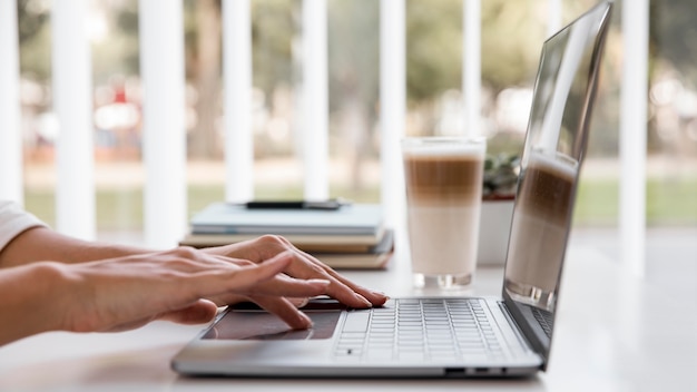 Side view of businesswoman working with laptop and having coffee