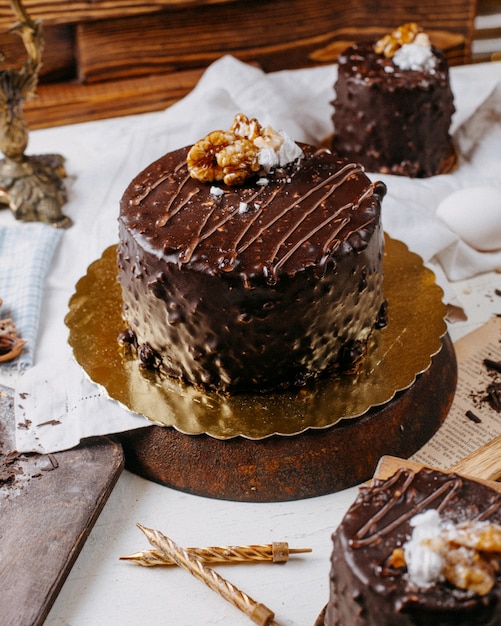 Side view of cake covered with chocolate and walnuts on the table