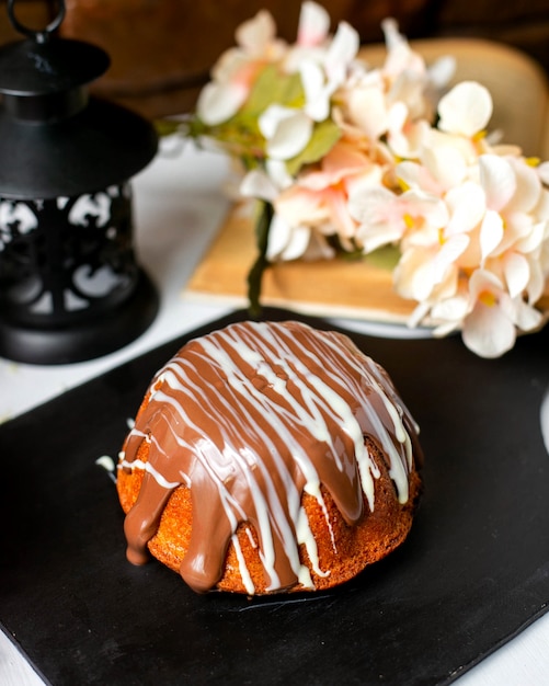 Side view of cake with chocolate sauce on a wooden board