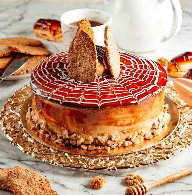 Side view of caramel cake with cookies on silver tray