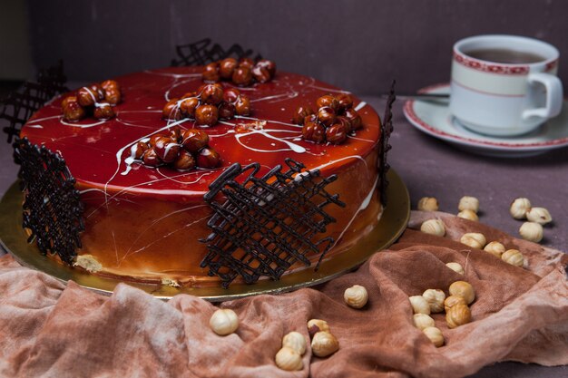 Side view caramel cake with nuts and cup of tea in rag