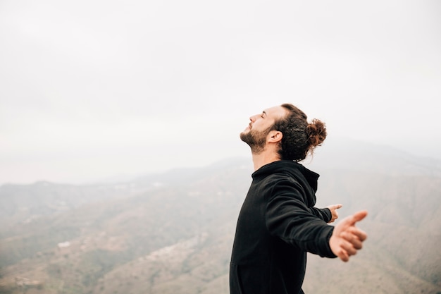 Side view of a carefree man enjoying freedom with arms outstretched