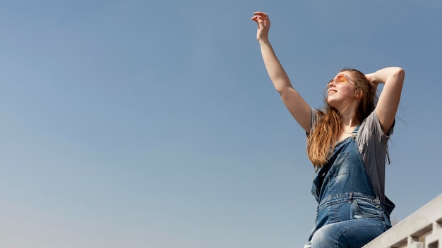 Free photo side view of of carefree woman posing with arm up and copy space