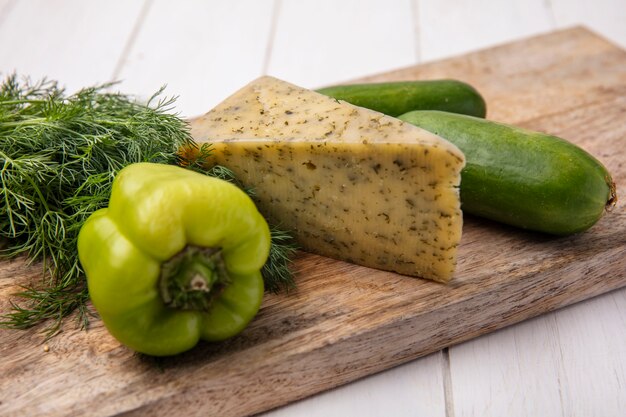 Side view cheese with cucumbers with bell pepper on a stand with dill on a white plate