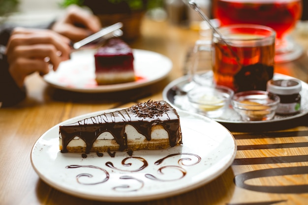 Side view of cheesecake covered with chocolate sauce on a plate