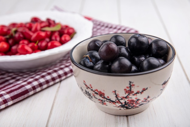 Side view cherry plum in a bowl with dogwood on a plate