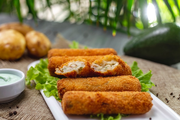 Side view chicken nuggets on lettuce leaves with sauce