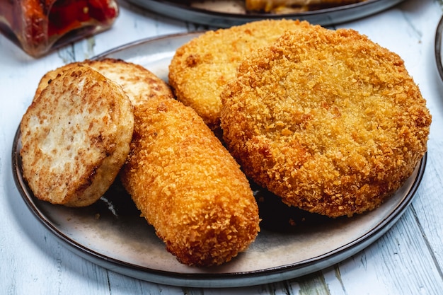 Side view chicken schnintzel with deep fried chicken strips and patty on a plate