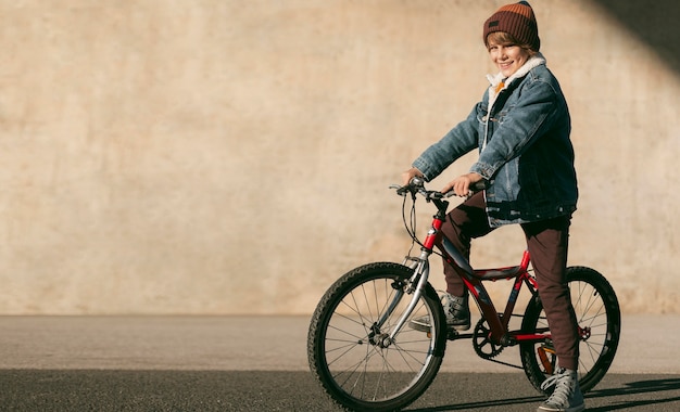 Free photo side view of child on bike outdoors with copy space