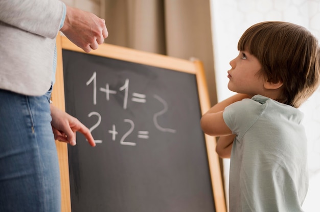 Free photo side view of child at home being taught mathematics