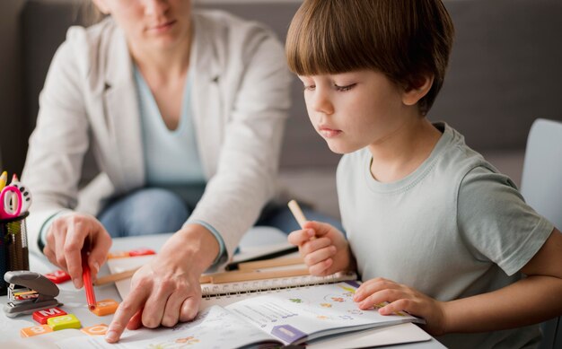 Side view of child learning from tutor at home