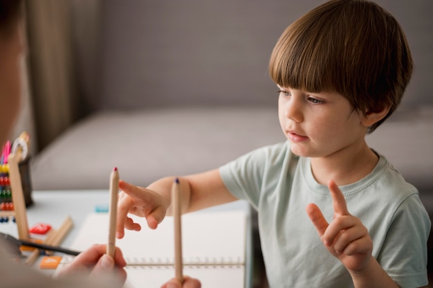 Side view of child learning how to count at home using pencils