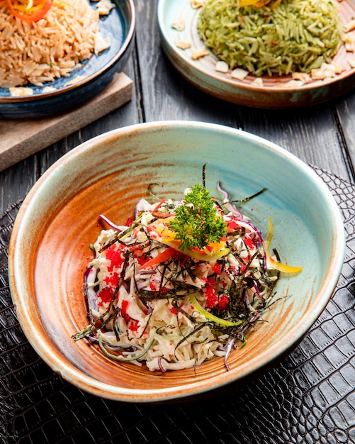 Free photo side view of chinese salad with chopped cabbage bell peppers and sea kale decorated with red caviar on a plate