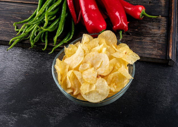 Free photo side view chips in bowl and chilli pepper on cutting board horizontal