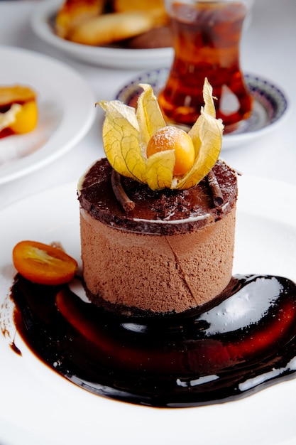 Free photo side view of chocolate cheesecake with kumquat served with tea