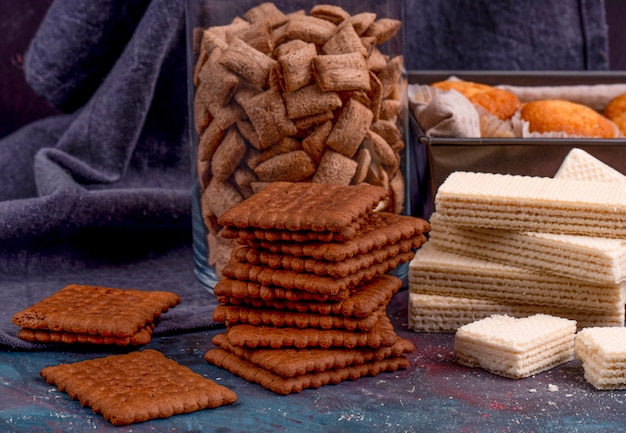 Side view of chocolate cookies and crispy waffles on dark background