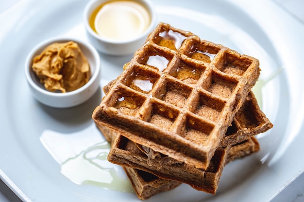 Side view chocolate waffle with honey on a board