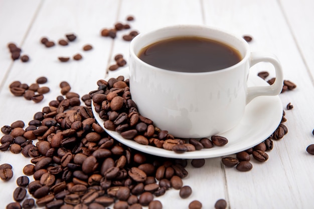 Side view of coffee on a white cup with coffee beans isolated on a white wooden background