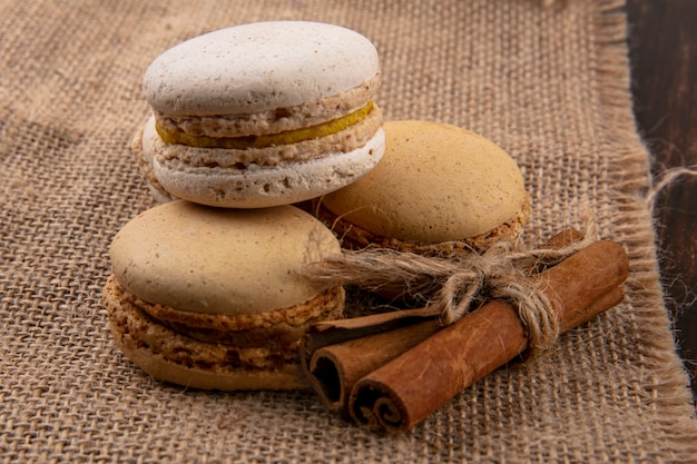 Side view of cookie sandwiches and cinnamon on sackcloth background