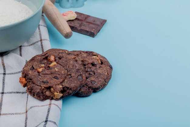 Free photo side view of cookies with flour chocolate on blue surface with copy space