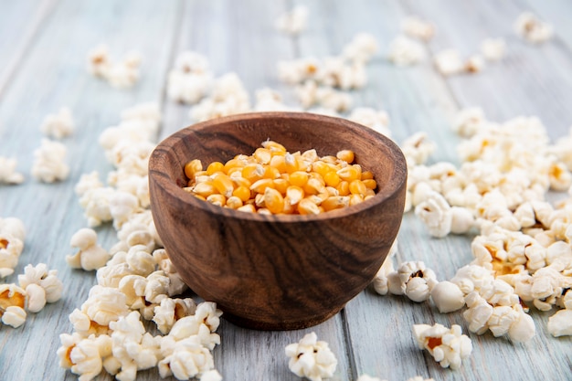 Side view of corns on a bowl with popcorn isolated on grey wooden surface