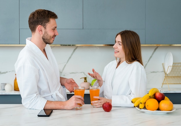 Side view of couple in bathrobes with glasses of juice