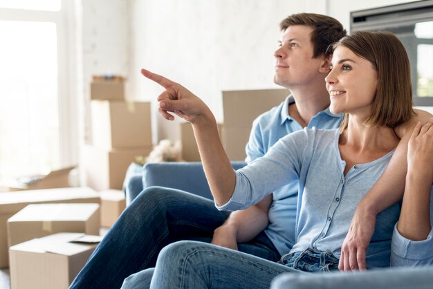 Side view of couple on the couch pointing at something while moving out