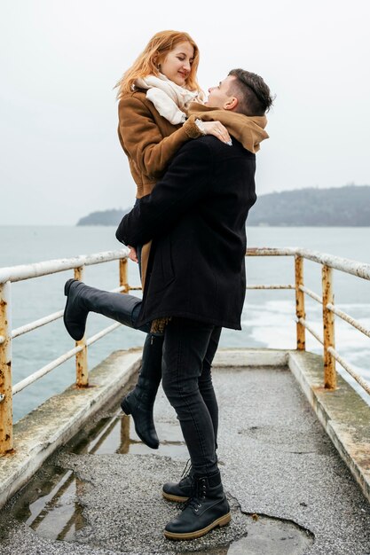 Side view of couple embraced by the lake during winter