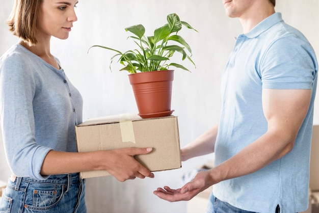 Free Photo side view of couple handling boxes and plant while preparing to move