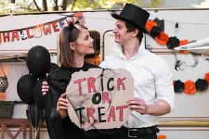 Free photo side view couple holding halloween sign